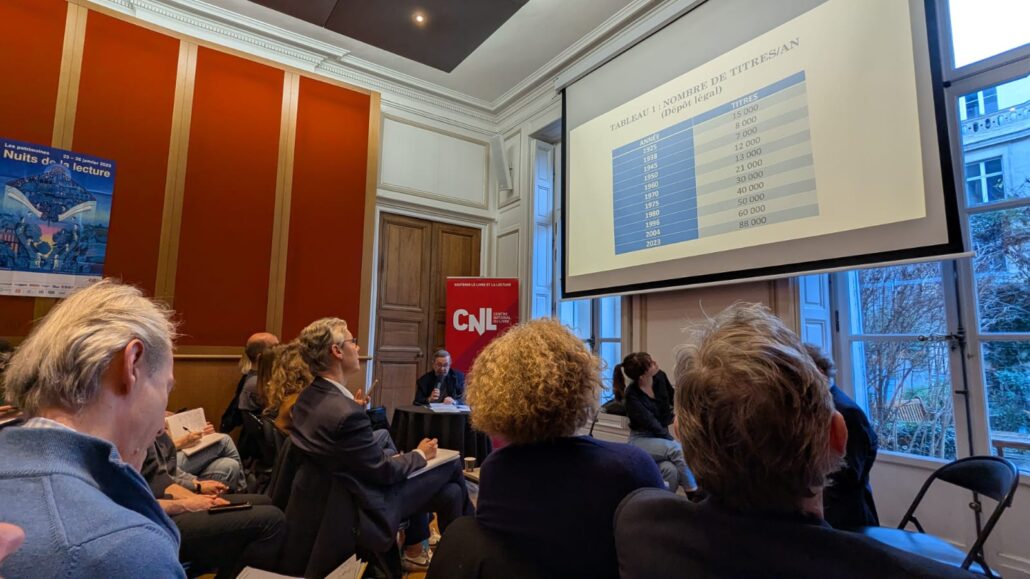 Personnes regardant un grand écran sur lequel sont affichés les chiffres des nouveautés littéraires en France